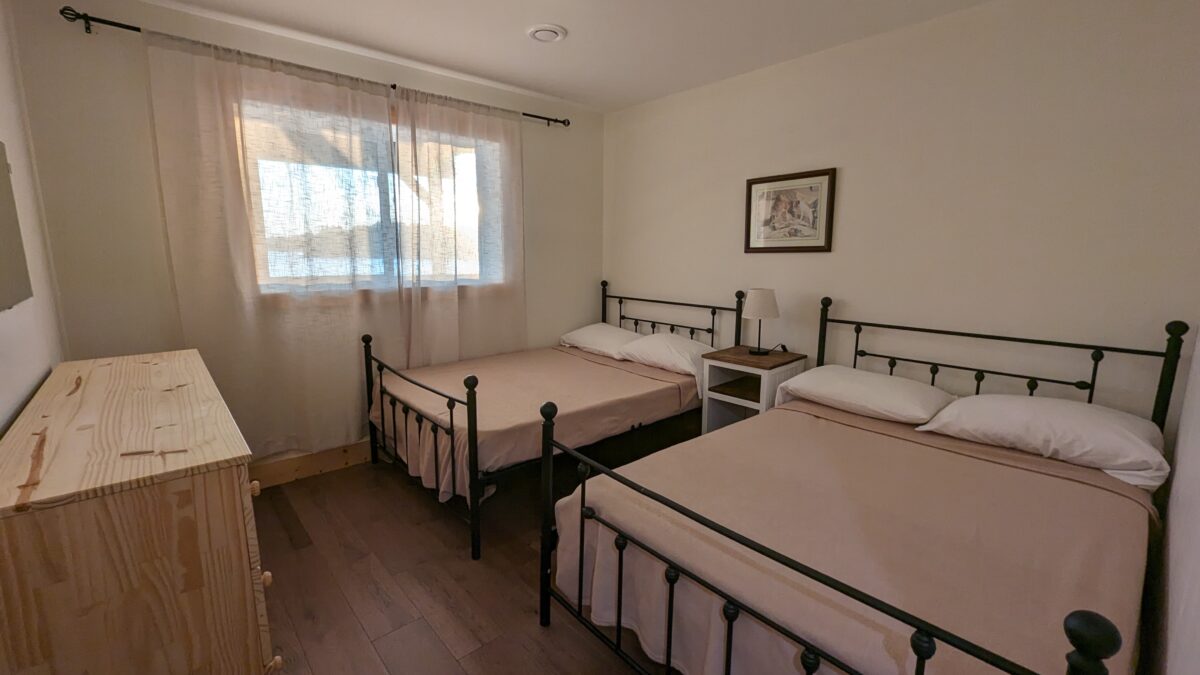 This spacious bedroom hosts two double beds, perfect for friends or family. Simple decor with ample storage space makes it both functional and inviting.